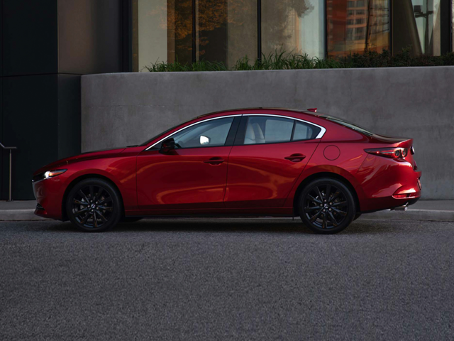 An image of a Mazda3 Turbo Premium Plus model in soul red crystal metallic, on a city street at dusk.