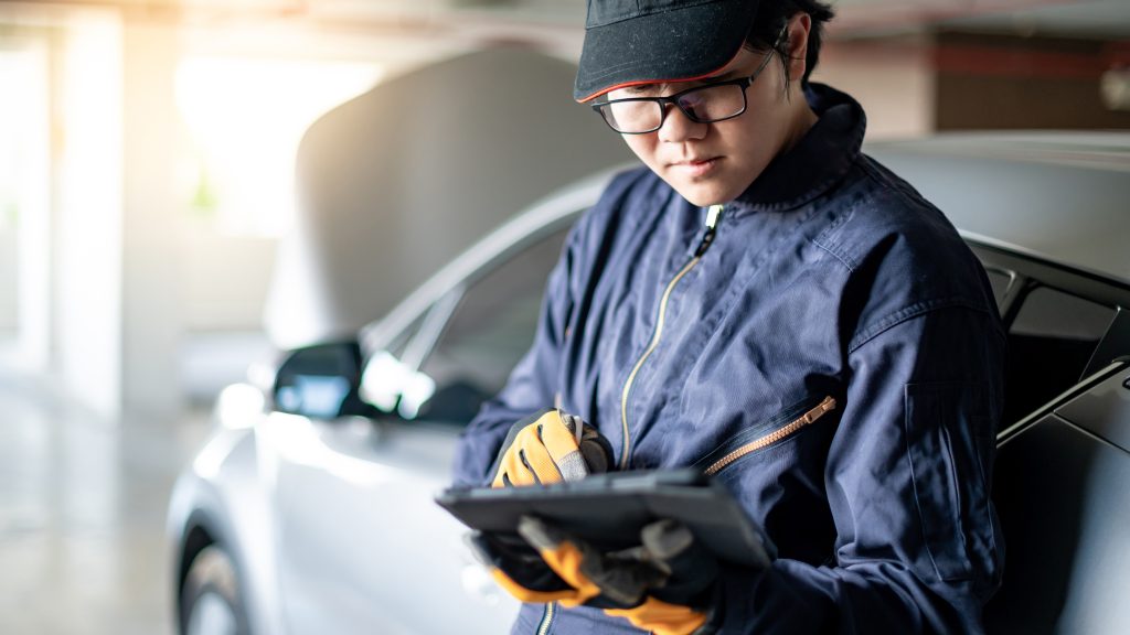 An image of a technician going over a vehicle's maintenance checklist on a clipboard. 