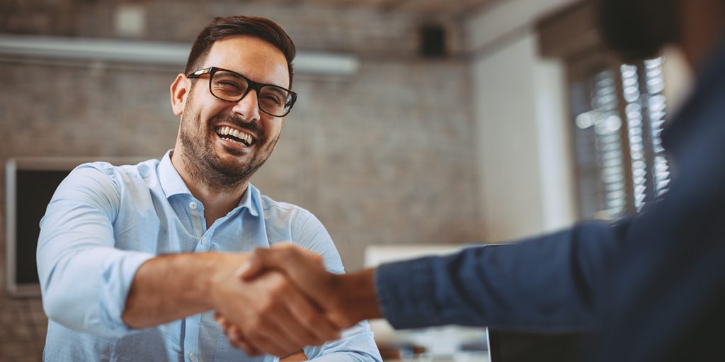 A happy customer shaking hands with a salesperson after trading in his vehicle.