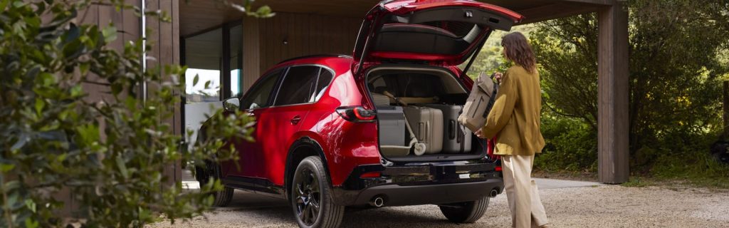 Red Mazda CX‑5 with open trunk and luggage being loaded.
