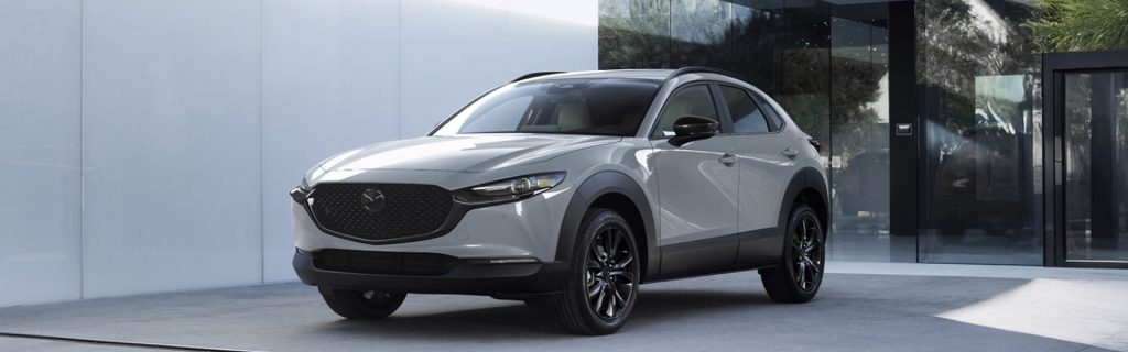 Silver Mazda CX‑30 parked outside a modern building, front angle view.