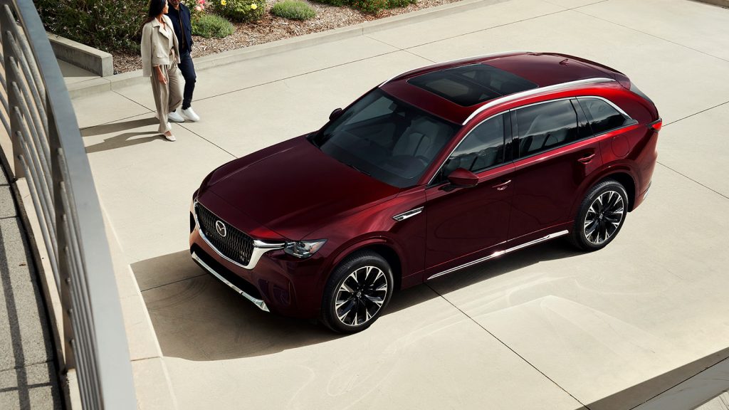 Couple walking toward a maroon 2026 Mazda CX-90 3-Row Family SUV