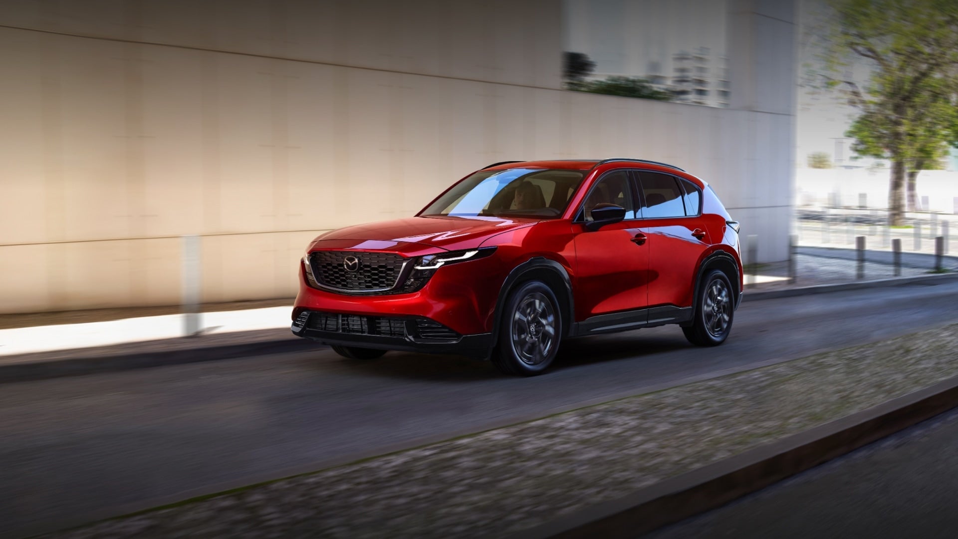Red Mazda CX-5 SUV driving through a city street.