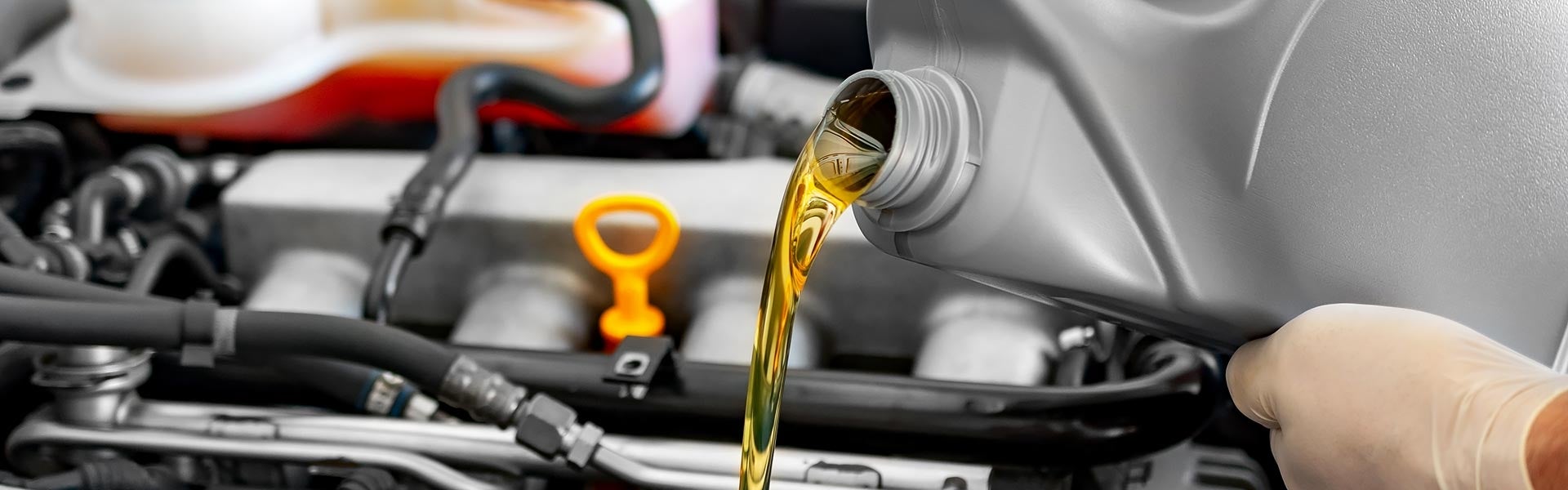 Oil being poured into a vehicle engine during an oil change.